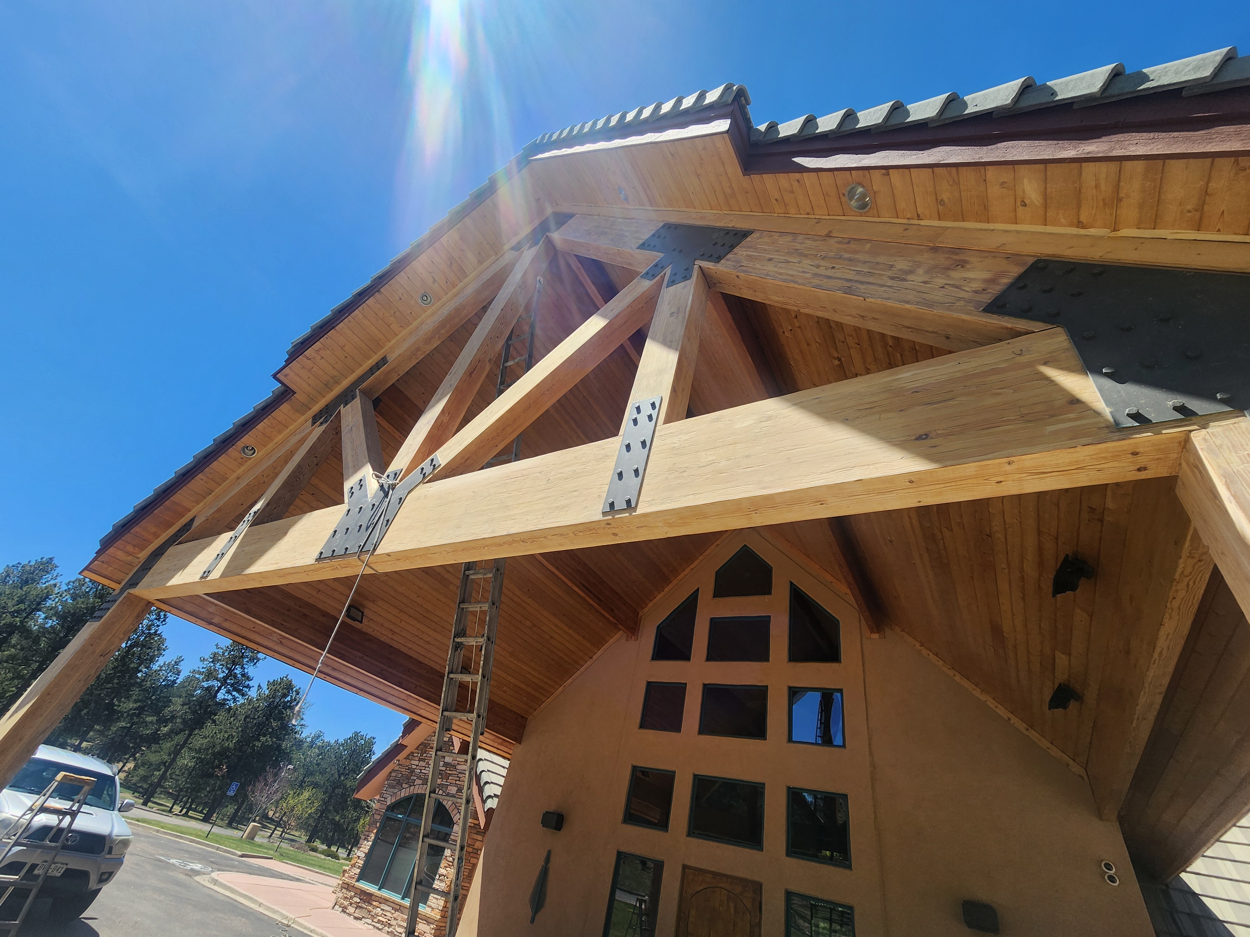 Image of Lodge exterior varnish. Image shows close up of cross beams and blue skies.
